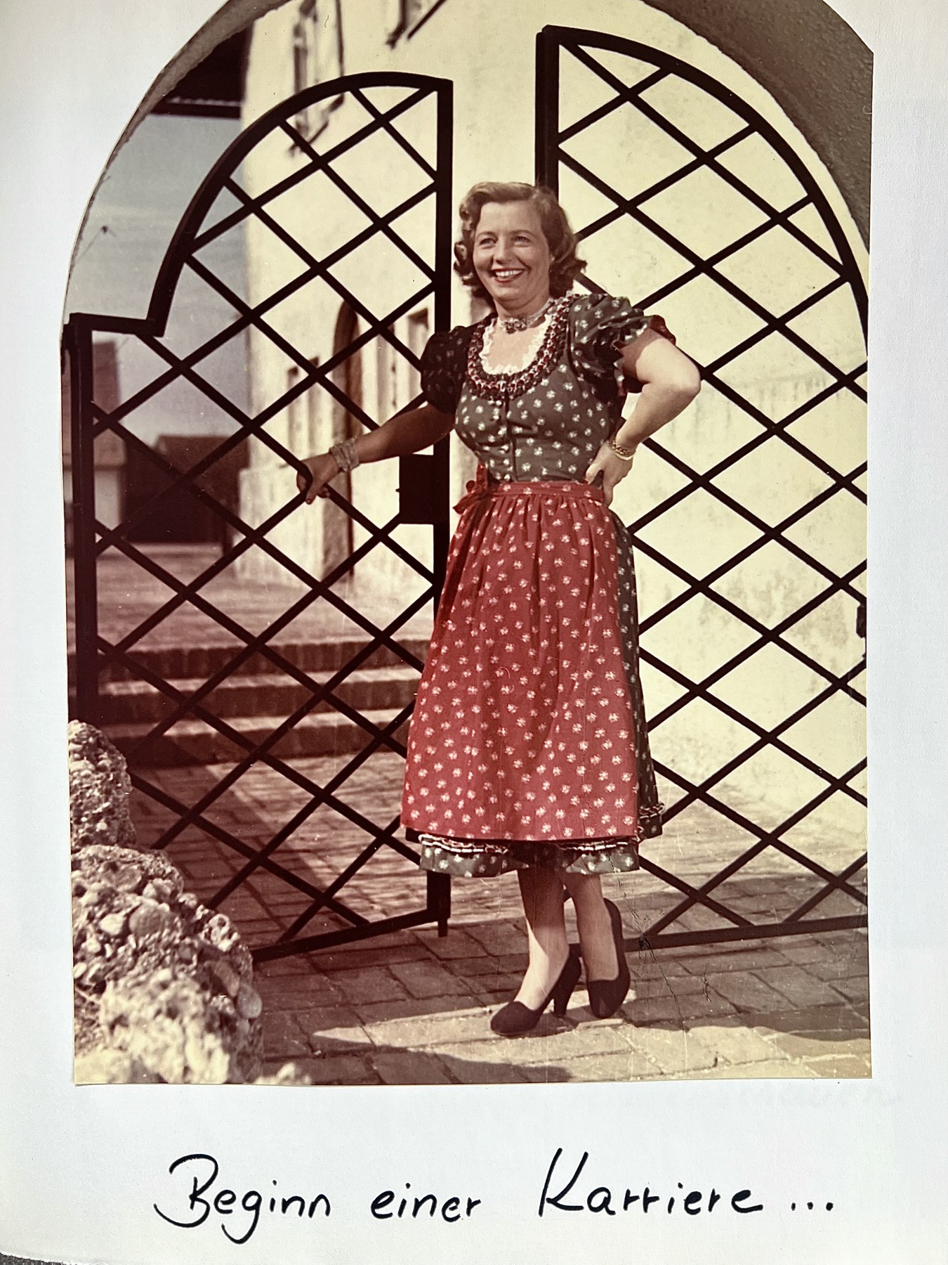 Ludwiga Preis in einem roten Dirndl vor einem schmiedeeisernen Tor
